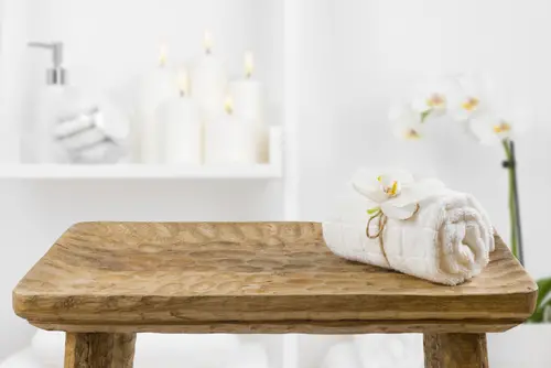 towel rolled up with flower on wooden bench