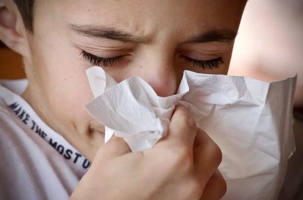 teen boy sneezing in paper tissue