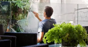Man in Gray Shirt Cleaning Clear Glass Wall Near Sofa